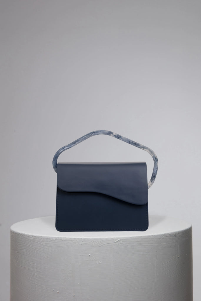 Navy geunine leather handbag on grey stand