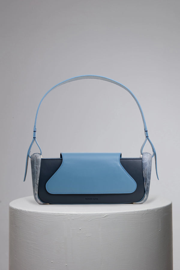 Blue geunine calf leather woman baguette bag on grey cylinder stand