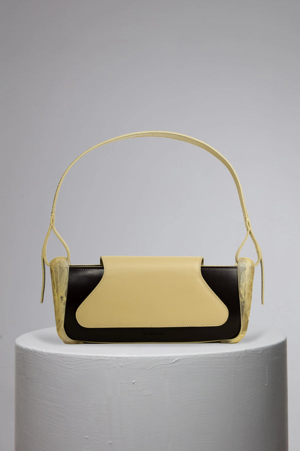 Yellowish geunine calf leather woman handbag with resin accessories on grey cylinder stand