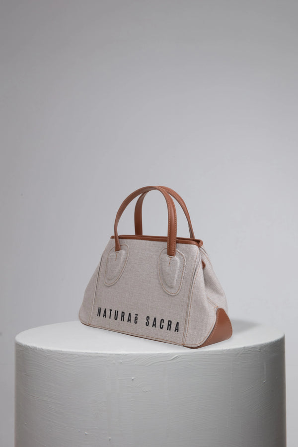 Canvas woman handbag with brand logo frony on grey cylinder stand