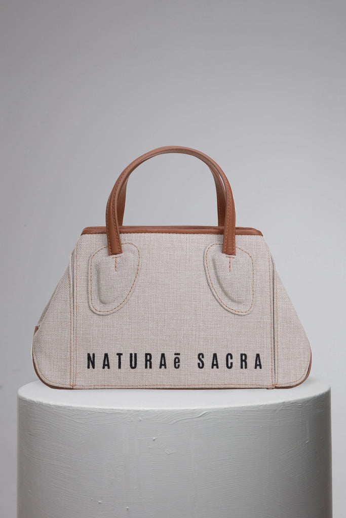 Canvas woman handbag w'th barnd logo front on grey cylinder stand