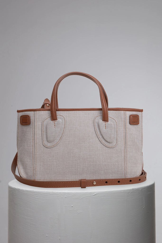 Canvas woman handbag with brand logo front on grey cylinder stand