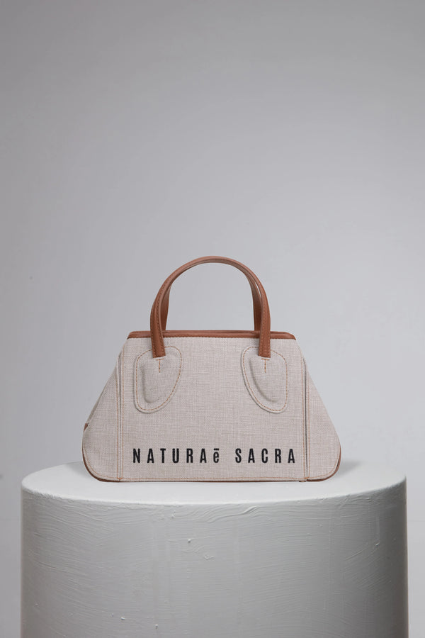 Canvas woman handbag with brand logo frony on grey cylinder stand