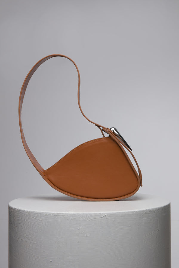 brown handbag with metal accessories on white stand