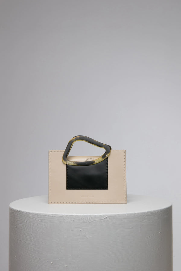 Rectangle shaped beige black colour calf leather saddle bag with natural resin handle holder and remowable calf leather handle strap on a white stand