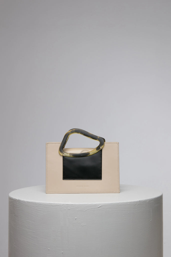 Rectangle shaped beige black colour calf leather saddle bag with natural resin handle holder and remowable calf leather handle strap on a white stand