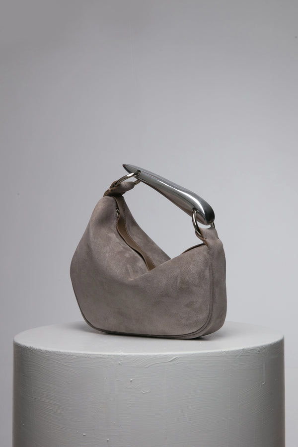 Grey suede leather soft handbag with metal handle on a white stand