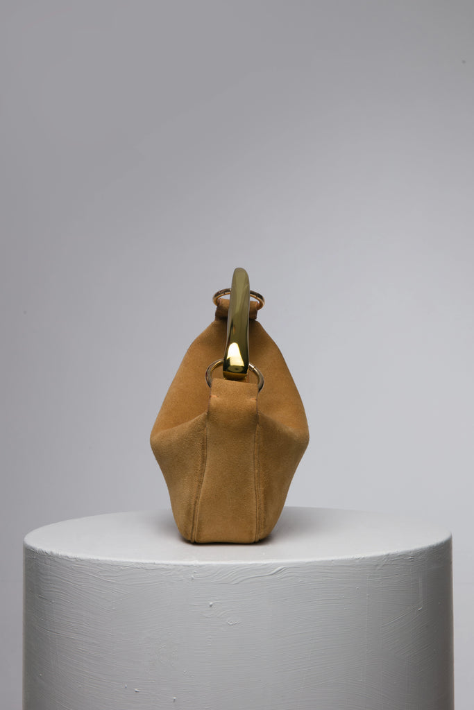 Brown suede leather soft handbag with metal handle on a white stand