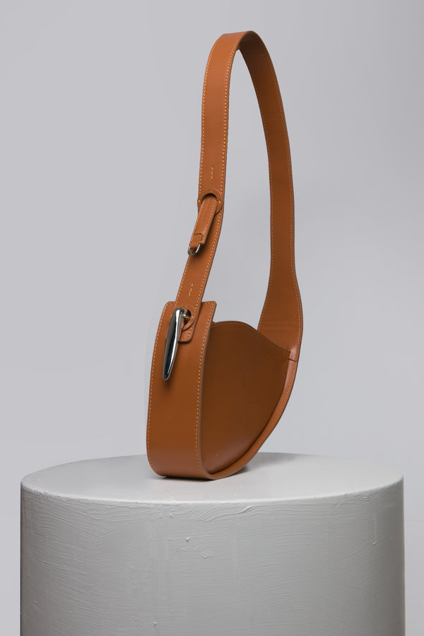 brown handbag with metal accessories on white stand