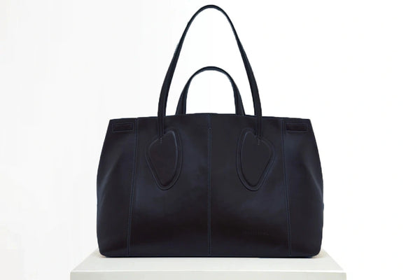 Calf leather maxi non-structured rectangle tote bag with non-removable two leather handle and two leather shoulder strap on a white stand