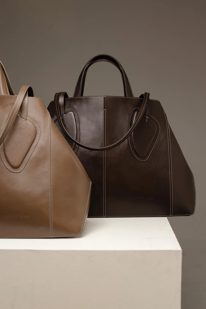 Calf leather maxi non-structured rectangle tote bag with non-removable two leather handle and two leather shoulder strap on a white stand