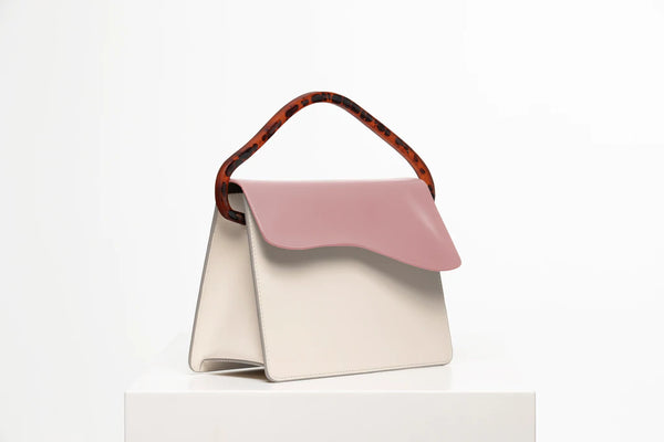 Rectangular women's bag with a bianco genuine leather body and dusty rose flap, bio resin handle and long shoulder handle, on a white stand in the studio