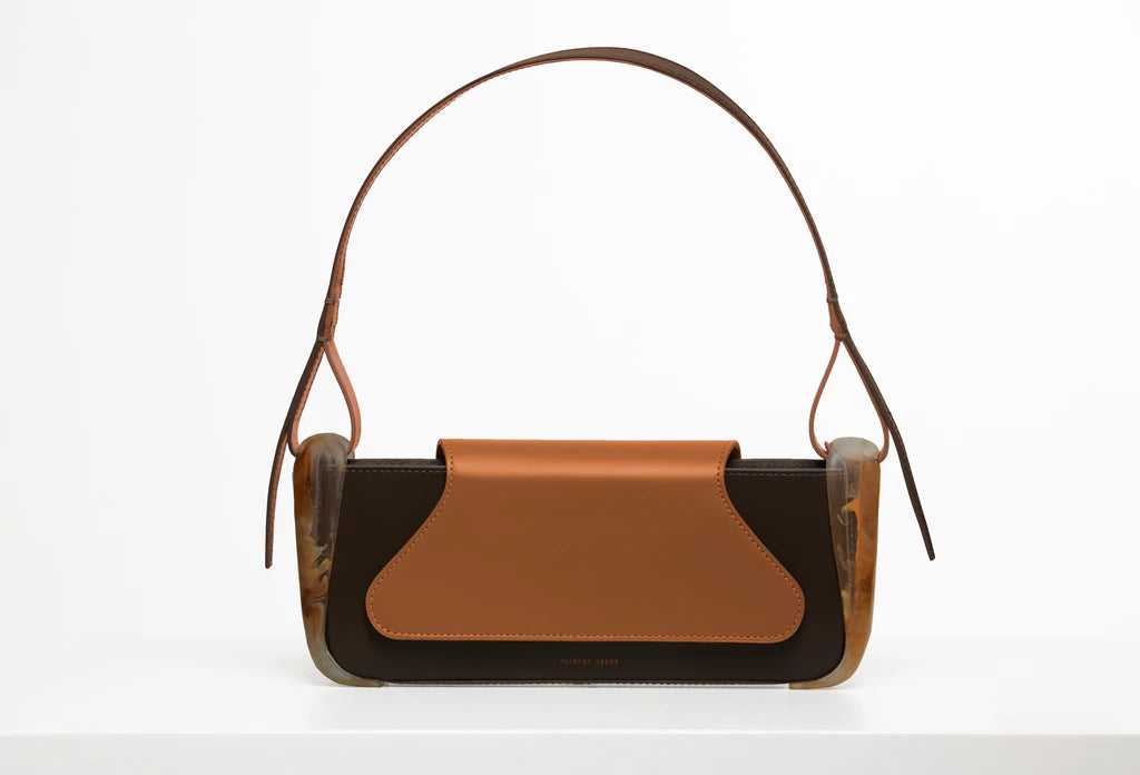 Brown calf leather rectangle baguette bag with special resin cover companents on the sides. non-removable shoulder strap on a white stand