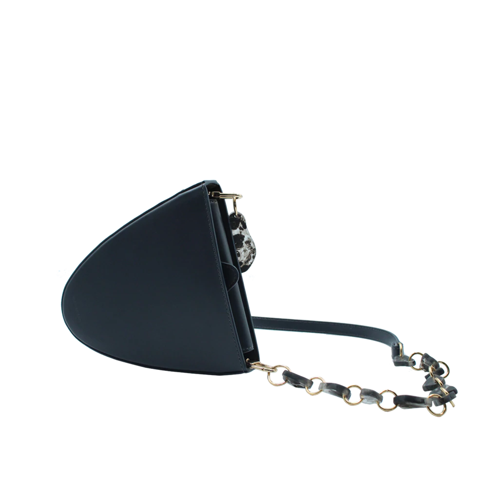 Flap topped oval structured anthracite calf leather cross body bag with an adjustable leather and natural resin chain linked strap on a white stand