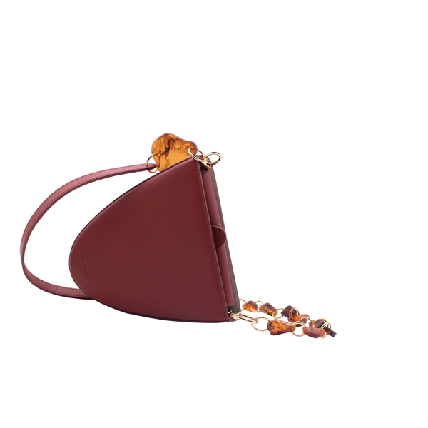 Flap topped oval structured brown calf leather cross body bag with an adjustable leather and natural resin chain linked strap on a white stand