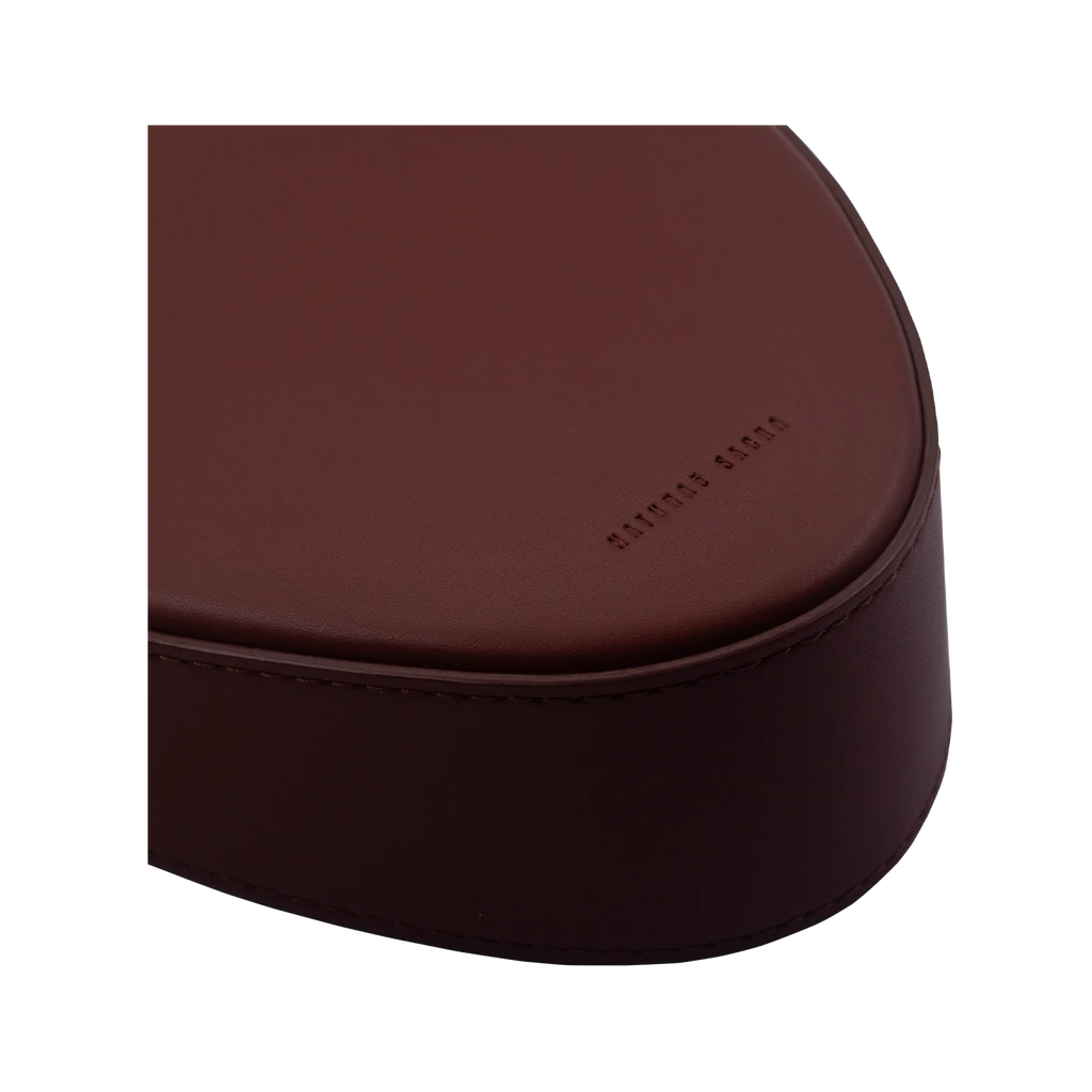 Flap topped oval structured brown calf leather cross body bag with an adjustable leather and natural resin chain linked strap on a white stand