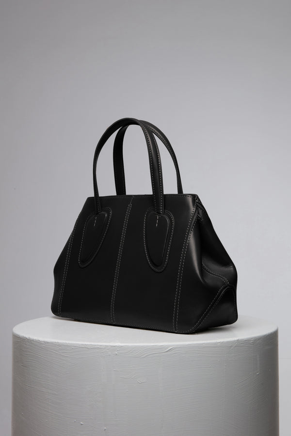 Black leather handbag over the white stand
