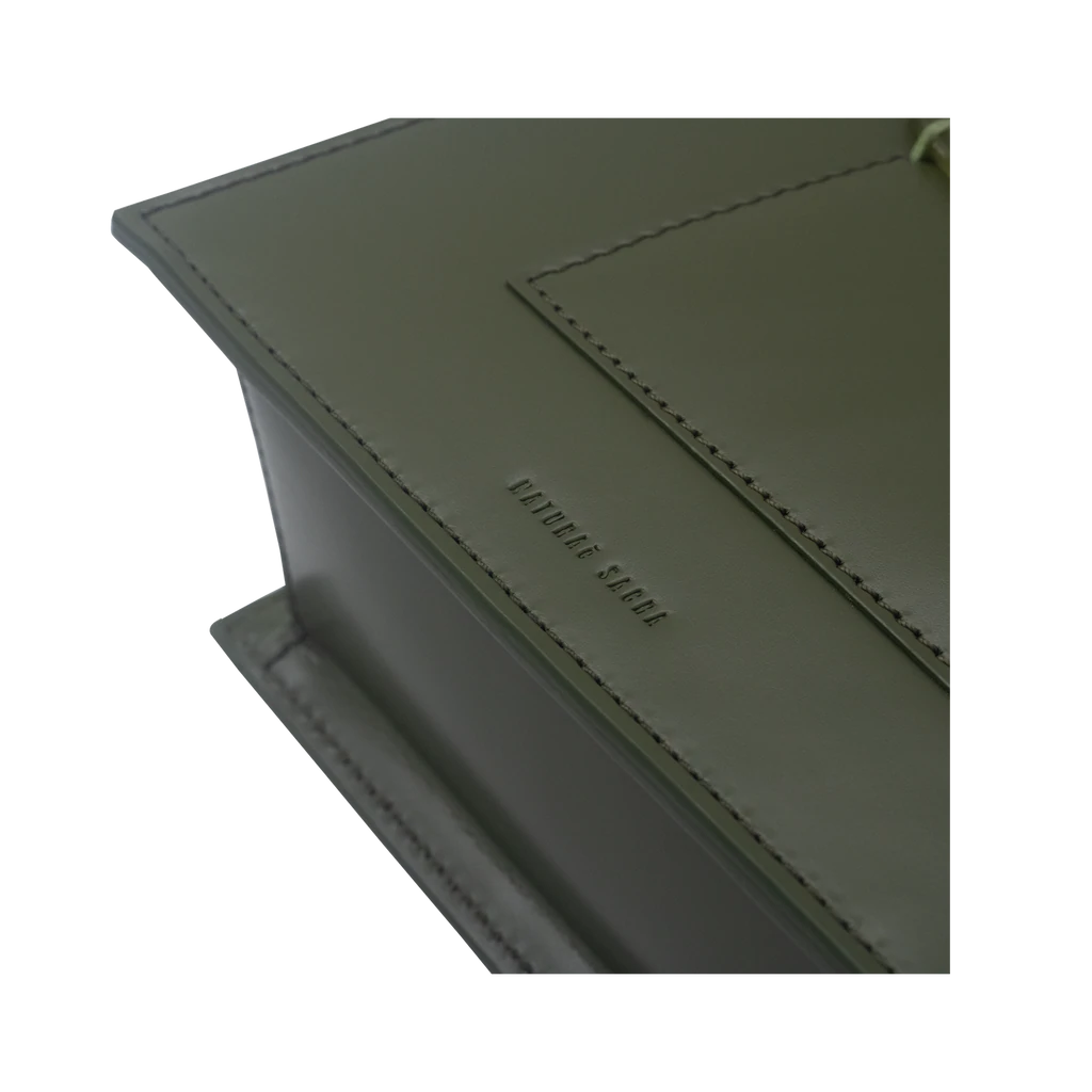 Rectangle shaped olive calf leather saddle bag with natural resin handle holder and remowable calf leather handle strap on a white stand