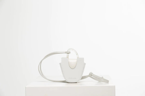 Mini flat topped oval structured off white calf leather tote bag with natural resin round handles and a removable adjustable calf leather strap