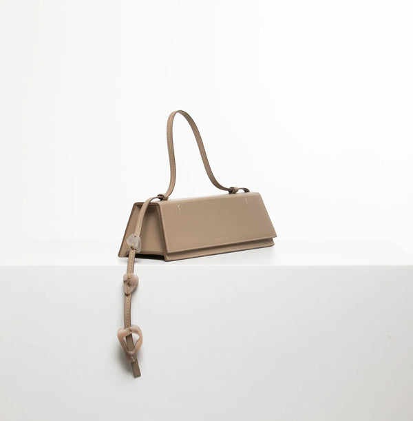 Rectangle shaped taupe calf leather clutch bag with natural resin filled in handles and removable calf leather handle strap on a white stand